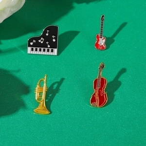 Set of four musical instrument enamel brooches featuring piano, guitar, and cello designs