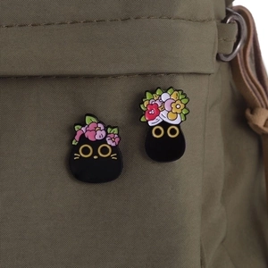 Cute black cat enamel pins with floral headpieces pinned on a canvas bag strap