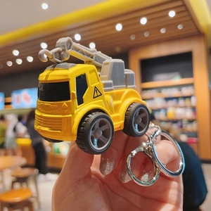Close-up of a yellow mini construction truck keychain with metal ring for kids