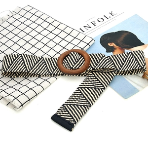 Detail of woven elastic belt with black and white geometric pattern and round wood buckle