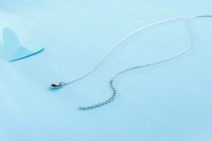 Détail du collier cœur en argent avec fermoir mousqueton et chaîne d'extension sur fond bleu