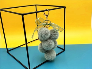 Detail of green faux fur grape keychain with satin bow on a metal geometric frame