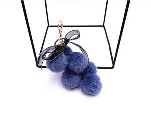 Close-up of blue faux fur grape keychain with black ribbon bow and metal clasp