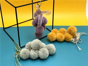 Plush grape keychains in purple and yellow with ribbon bows on a modern display