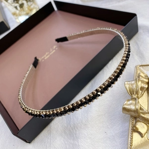 Detailed close-up of a slim metal headband with black and gold crystal bead decoration
