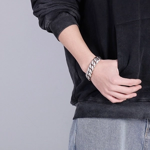 Close-up of a thick silver Cuban chain bracelet on a male wrist for a rugged style