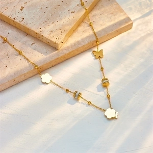 Collana chic in titanio dorato con pendenti a farfalla in conchiglia e quadrifoglio