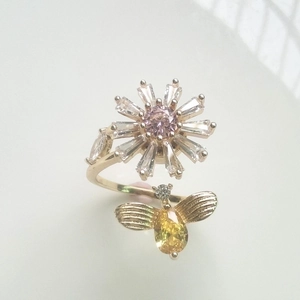 Detailed macro view of rotating daisy and bee ring with pink and yellow crystal stones