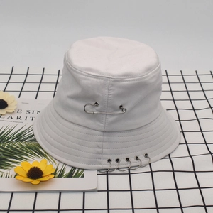 Detailed shot of white cotton bucket hat with silver pins and rings in punk street style