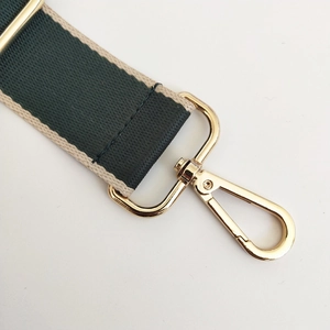 Detail of dark green woven bag strap with gold lobster clasp and adjustment buckle