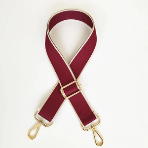 Macro view of adjustable burgundy and cream woven shoulder strap with gold metal hooks