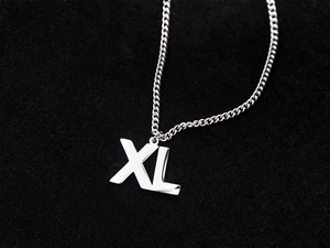 Macro shot of silver XL letter pendant necklace on black velvet with metallic luster