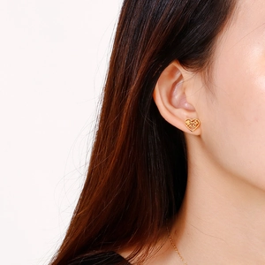 Golden heart stud earring with hollow floral design and 'mae' lettering on model