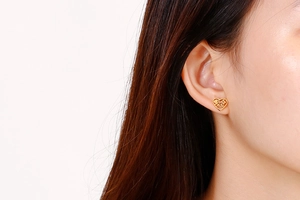 Close-up of heart-shaped gold earring with Mama engraving worn by a model