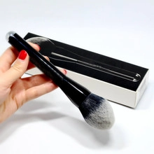 Close-up of a premium large makeup brush with a black handle and gradient soft bristles