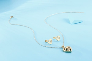 Vue détaillée d'une parure de bijoux cœur évidé doré avec collier et boucles d'oreilles