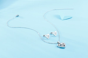 Détail macro d'un ensemble bijoux cœur argenté avec motif arbre et boucles d'oreilles