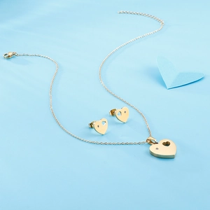 Golden heart jewelry set with necklace and stud earrings on light blue background