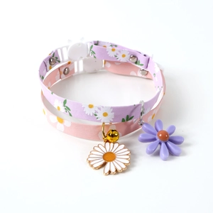 Detail of adjustable pet collars in lavender and pink with daisy patterns and bells