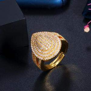 Adjustable gold teardrop ring with pave cubic zirconia on a textured black background