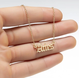Detailed hand-held view of the gold Aries zodiac pendant necklace with thin chain