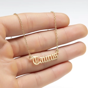 Close-up of golden Taurus zodiac pendant necklace held by hand showing fine craftsmanship