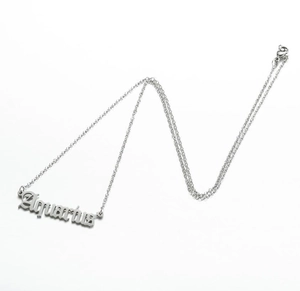 Macro shot of silver Aquarius zodiac letter pendant on a minimalist stainless steel chain
