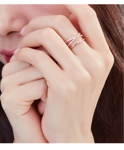 Close-up of rose gold layered rings with X-shaped pavé accents and a single solitaire gem