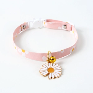 Detail of pink fabric pet collar with daisy patterns, gold bell and quick-release safety buckle