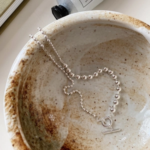 Detail of silver beaded necklace with OT toggle clasp inside a ceramic bowl