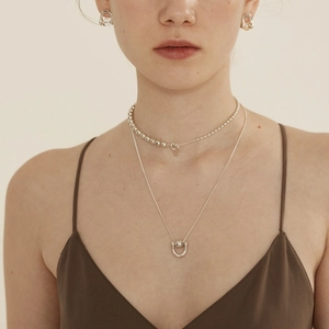 Detail of minimalist 925 sterling silver ball choker and horseshoe pendant necklace set