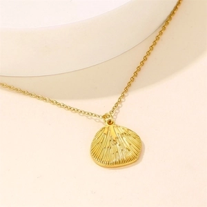 Golden shell pendant necklace with ribbed texture on a minimalist beige background