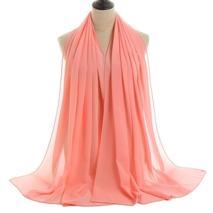 Detailed texture of coral pink chiffon headscarf draped gracefully on a mannequin