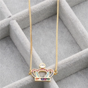 Detailed close-up of golden crown pendant with multi-colored gemstones in jewelry box