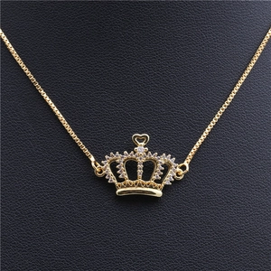 Detail of gold crown pendant with cubic zirconia on box chain over black leather