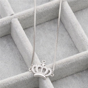 Macro shot of silver crown pendant necklace with micro-set zircons on grey velvet tray