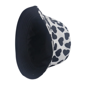 Detailed view of white bucket hat featuring black heart patterns and black inner lining