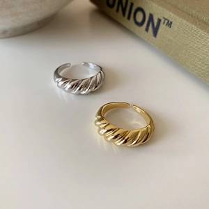 Detail of vintage croissant twist open rings in gold and silver finish on a book