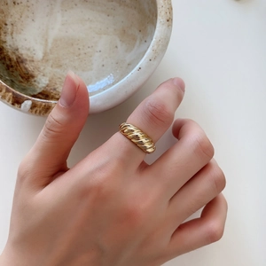 Detail shot of a model wearing a thick golden twisted dome ring on the index finger