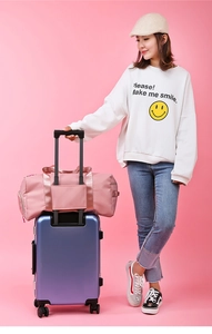 Pink travel bag with luggage strap sleeve attached to a purple trolley suitcase