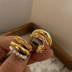 Close-up of 18K gold-plated twisted metal earrings with white pearl inlay details
