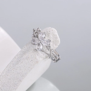 Silver flower ring with zircon petals and vine band on a textured stone display