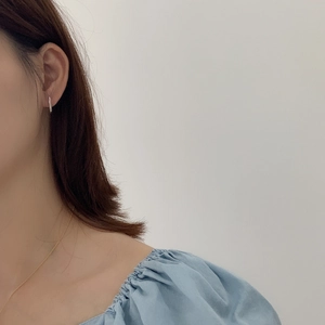 Close-up of minimalist silver vertical bar earrings and fine gold chain necklace on model