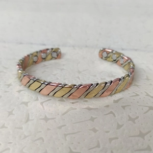 Detail of copper twisted magnetic bracelet showing interior therapy magnets on white pad