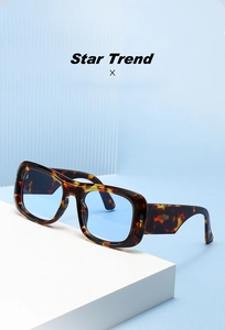 Detail of chunky tortoise frame sunglasses with blue tinted lenses on white steps