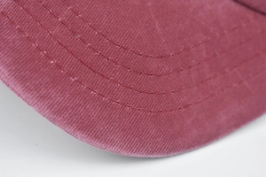 Close-up of deep red twill cotton baseball cap brim with stitching and vintage worn edges