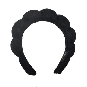 Detail of black twisted sponge headband showing the handmade label and soft towel texture