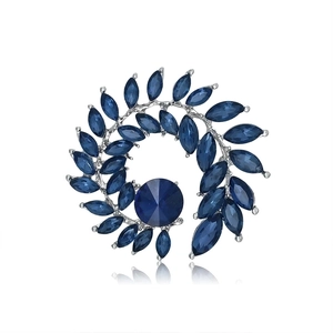 Macro shot of silver cactus brooch with sparkling blue gemstones and elegant spiral design