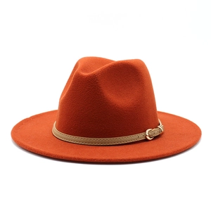 Detail of wide-brimmed brick red wool fedora with beige leather band and gold buckle
