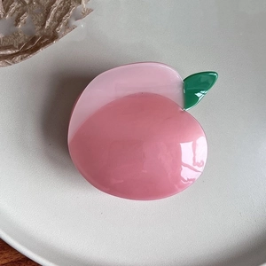 Macro detail of high-quality acetate peach hair claw clip with green leaf on ceramic plate